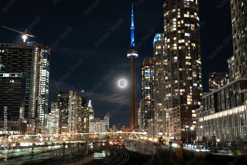 Night view of Toronto city skyline illuminated by a full moon in the sky in Canada