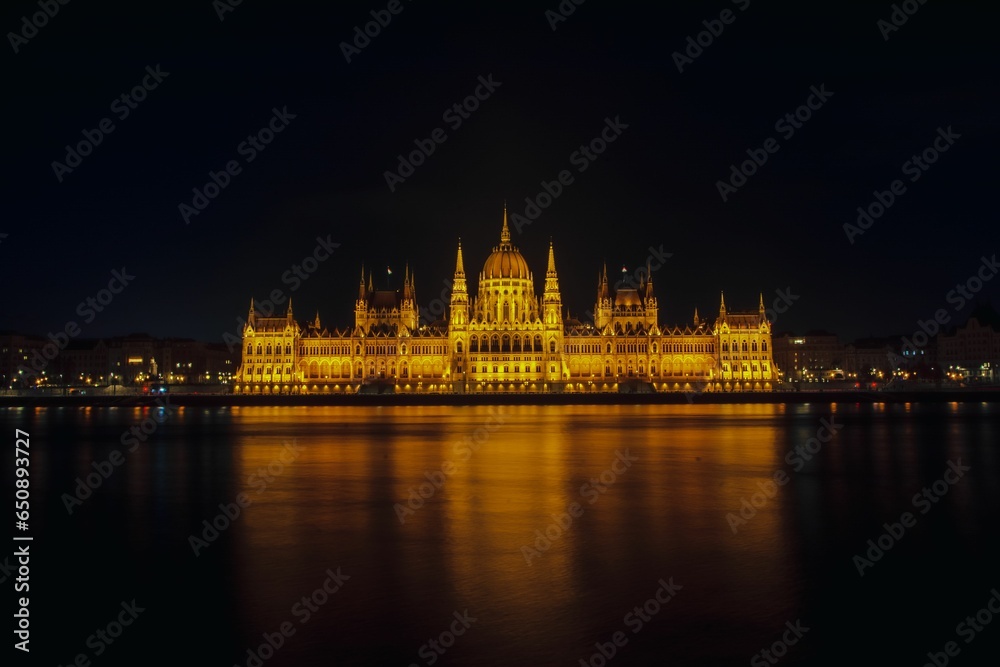 parliament building on parliament square lit up at night by the danube river