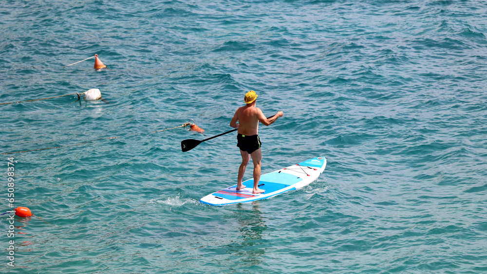Naklejka premium Młoda dziewczyna w stringach płynie na materacu po morzu.