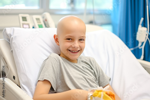 Portrait of a bald young boy smiling in cancer hospital bed. Children with cancer concept