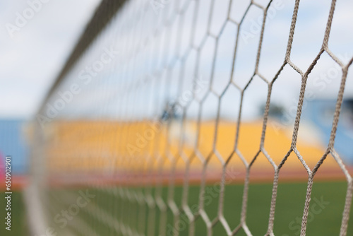 Close-up of soccer goal net in stadium against blue and yellow fan zone