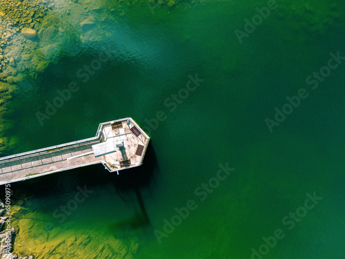 An aerial view of a water treatment plant surrounded buy deep green water and yellow/gold moss covered rocks in the Yan Yean Reservoir in Melbourne, Australia.