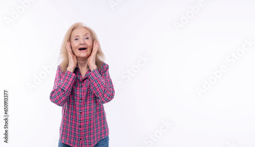 Excited surprise grandmother raised hands on face smiling joyful looking camera over isolated white background.Shocked winner healthy mature elderly woman holding hands beside mouth looking copy space