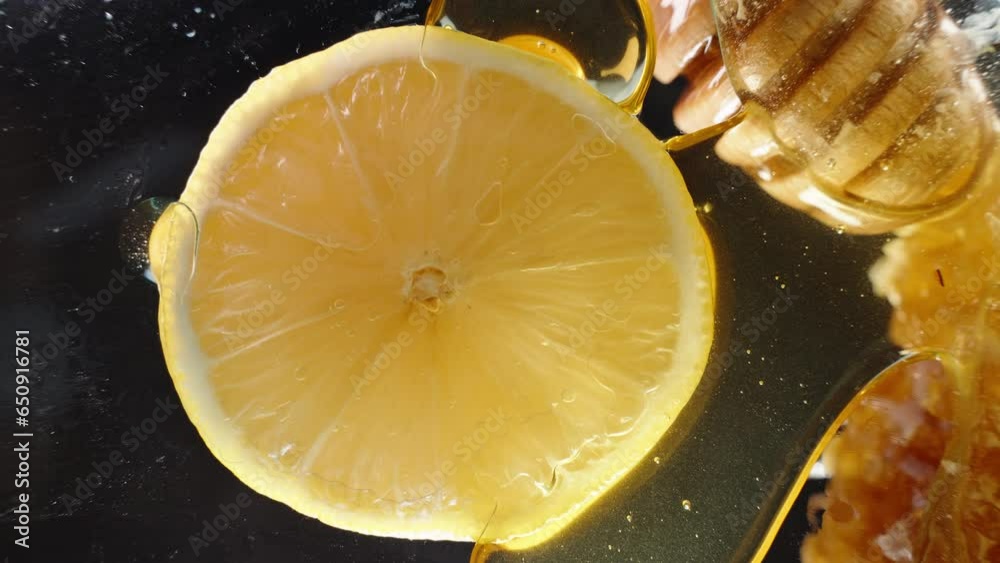 A view from below of a lemon slice through a glass table as honey drips from it. Close-up.