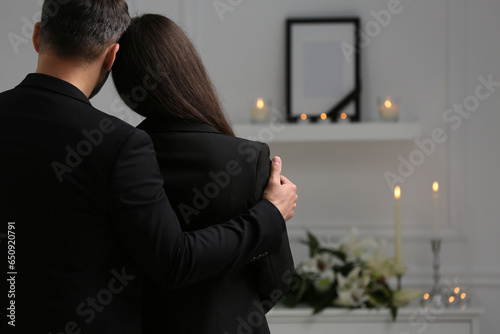 Couple mourning indoors, back view and space for text. Funeral ceremony