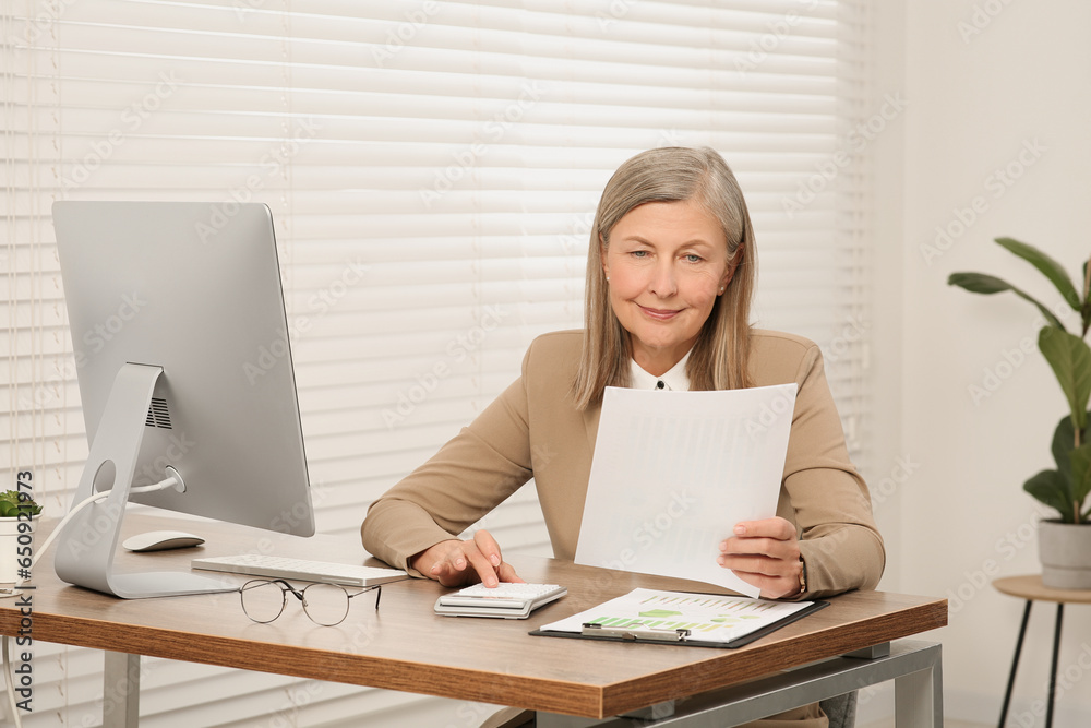 Senior accountant working at wooden desk in office Senior accountant working at wooden desk in office