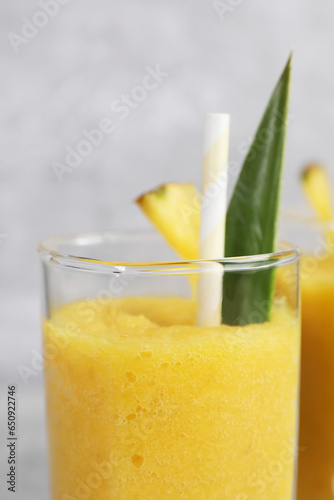 Tasty pineapple smoothie on light gray background, closeup