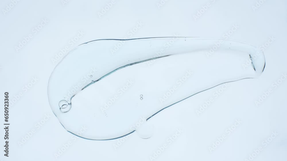 Spatula applies smear of shampoo or shower gel on white background, top view.