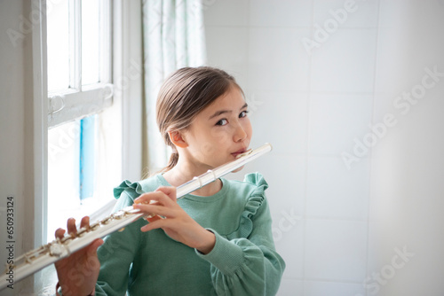 窓辺でフルートを吹いている女の子 photo