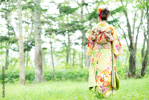 森林の中に立つ着物姿の女性の後姿