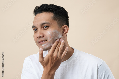 Photo of a young Asian man with cream for problem skin applied onto the face, close-up concept.