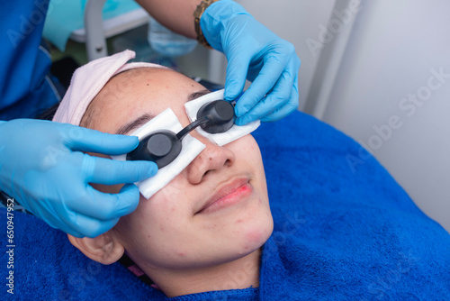 A patient is worn goggles on top of gauze to protect the eyes during LED light or laser therapy at an aesthetic clinic.