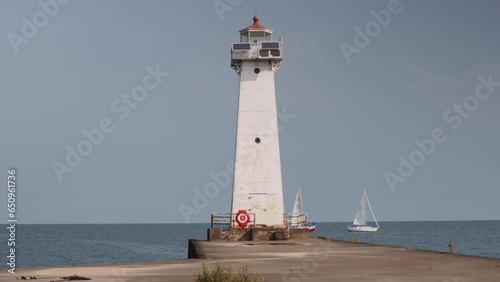 Two boats passing the small lighthouse shot of the light houses at Sodus point New York vacation spot at the tip of land on the banks of Lake Ontario. photo