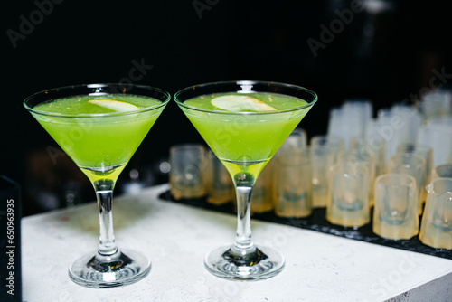 Green cocktail in a martini glass on a bar counter in a nightclub