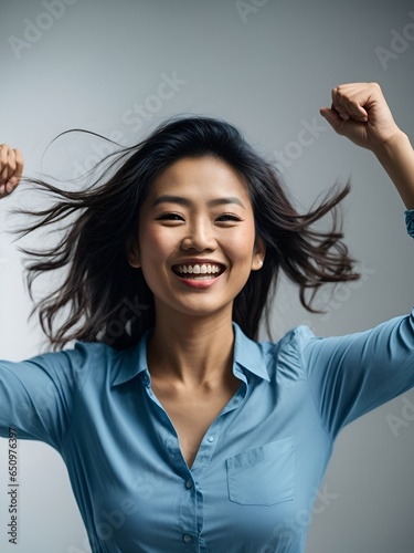 Excited Asian woman wearing a blue shirt showing strong gesture
