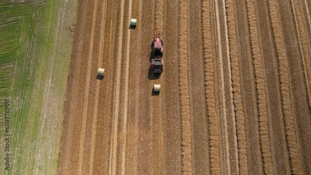 Top down aerial of a tractor working in the field during straw baling. Modern agriculture full of technological solutions. Top down aerial of a tractor working in the field during straw baling. Modern agriculture full of technological solutions.