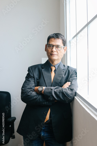 Closeup of successful mature Asian businessman standing with folded arms and looking at camera confidently