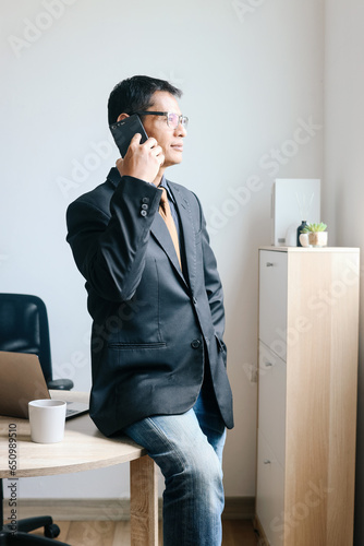 Successful Asian mature businessman having a phone call in modern office