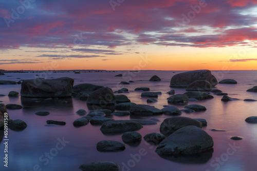 Late red sunset view of rocky sea shore, damatic light, long exposure photo