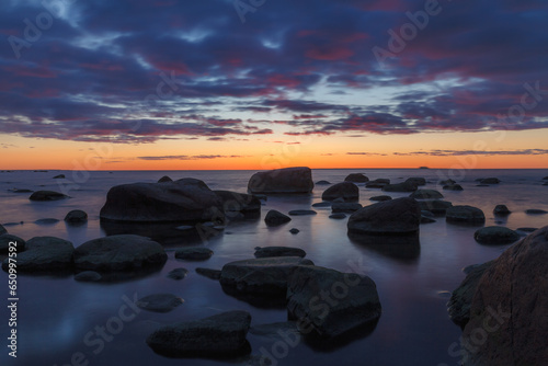 Late red sunset view of rocky sea shore, damatic light, long exposure
