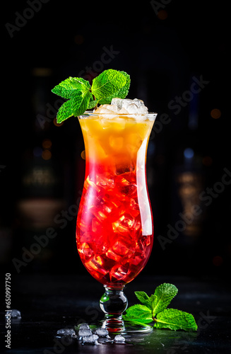 Aruba Ariba summer cocktail drink with vodka, white rum, orange, lemon and pineapple juice, grenadine syrup, dark bar counter background