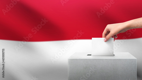 Woman puts ballot paper in voting box on Indonesia flag background. Election concept.