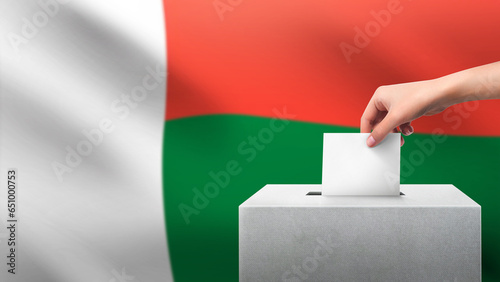 Woman puts ballot paper in voting box on Madagascar flag background. Election concept.
