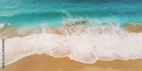 Aerial view of beautiful beach with turquoise water and white sand. Top view of a beach with waves breaking on the sand. 