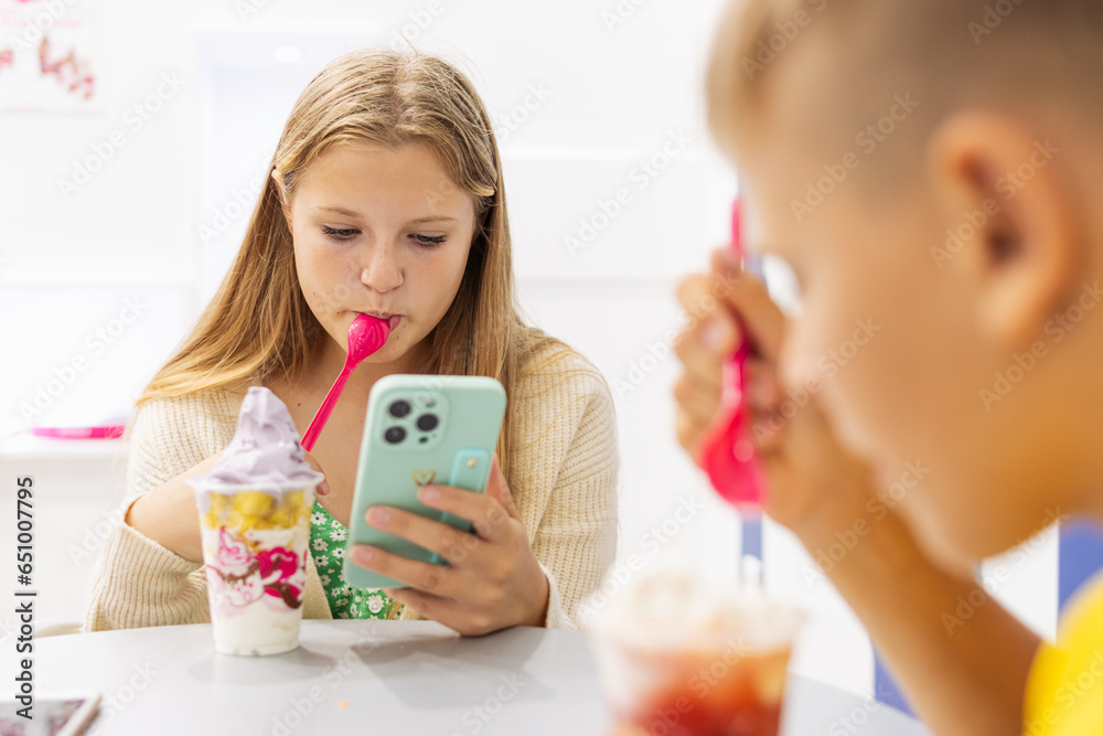 boy and a girl eat ice cream in a summer cafe in a summer cafe,a girl looks at a photo on her phone boy and a girl eat ice cream in a summer cafe in a summer cafe,a girl looks at a photo on her phone