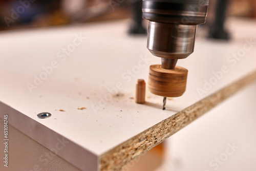 Drill holes for attaching furniture legs. Assembling cabinet furniture.