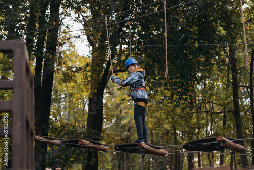 teenage boy in outdoor adventure park passing obstacle course. high rope park