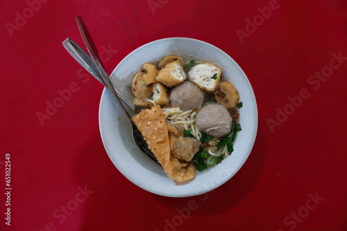 A bowl of soup containing noodles, meatballs, fried tofu and dumplings photo
