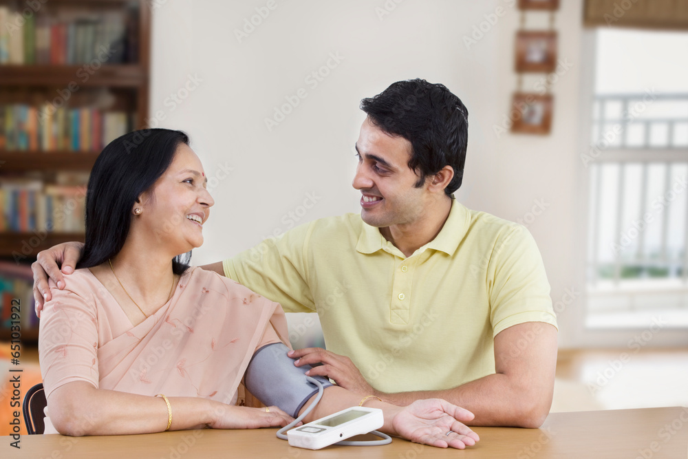 Young man checking mother's blood pressure Young man checking mother's blood pressure