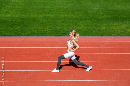 Physical training girl. Fit girl do outward lunging. Physical training education. Sports lesson. Female runner stretching before workout. Sports exercises and stretching in the stadium
