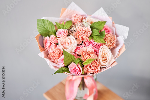Fototapeta Naklejka Na Ścianę i Meble -  Beautiful bouquet of fresh flowers in glass vase on wooden table. A gift bouquet in mix color scheme for any holiday. The concept of a small flower shop. Flower and gift delivery
