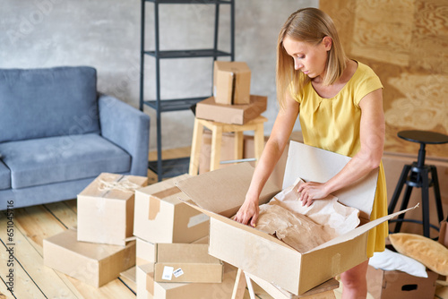 Young girl packing plates into the boxes ready to move. Woman unpacking moving boxes in her new home. unpack personal stuff from carton boxes.
