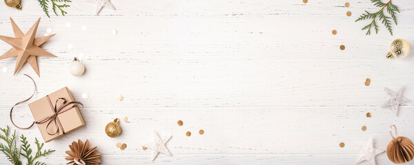 Festive Christmas background with gift box and Christmas decorations on white wooden table. Top view. Copy space for text.