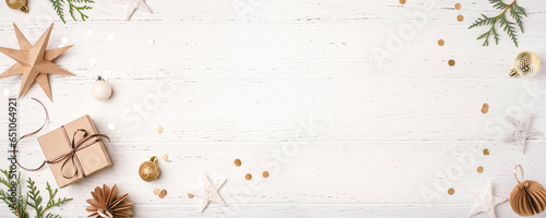 Festive Christmas background with gift box and Christmas decorations on white wooden table. Top view. Copy space for text.