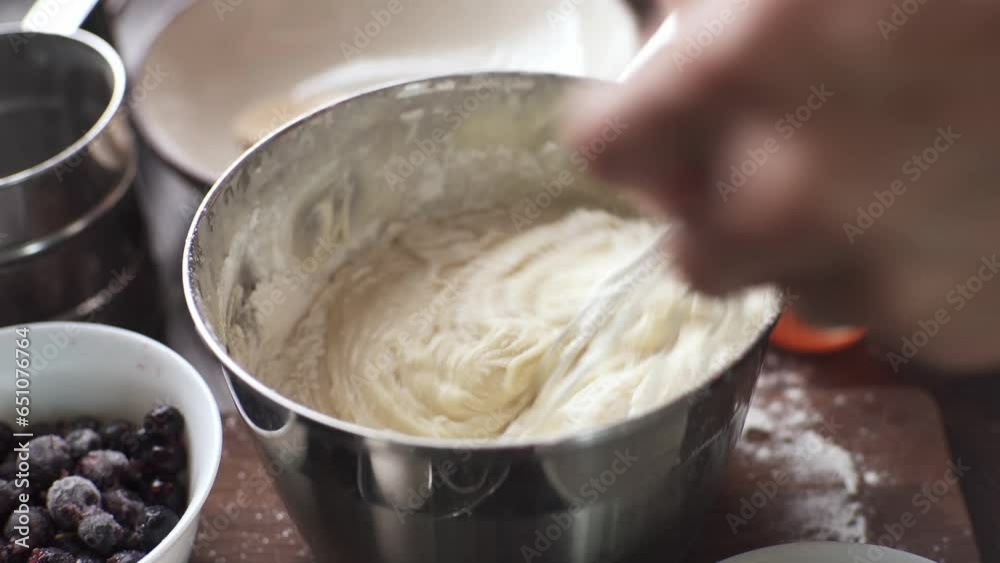 The pastry chef whips the dough for cupcakes with a whisk. Top view of the table with products. Cooking delicious confectionery at home The pastry chef whips the dough for cupcakes with a whisk. Top view of the table with products. Cooking delicious confectionery at home