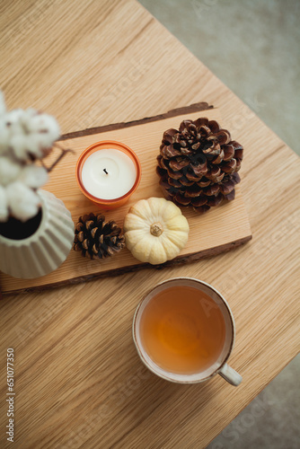 Autumn decor. Hot drink. Mug of tea, book, pumpkin, candle on a wooden coffee table. Autumn.