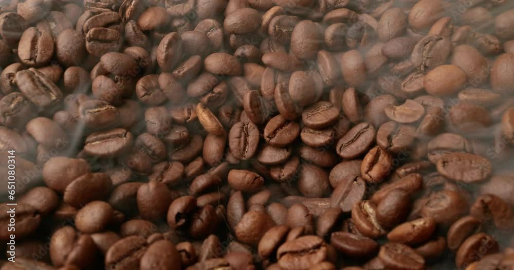 Close up of seeds of coffee. Fragrant coffee beans are roasted smoke comes from coffee beans.