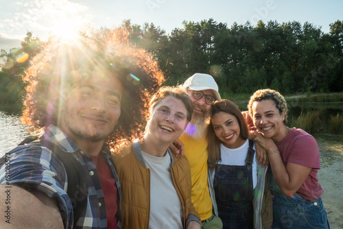 Multiracial young group of trendy people having fun together on vacation - Diverse millennial friends taking selfie portrait together while enjoying free time on a forest lake beach - Friendship #651085573
