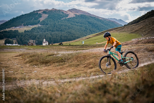 Active young boy rides a bicycle. Little rider rides mountain bike. Enduro riding in the mountains photo