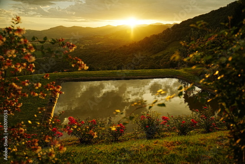 amanecer desde la montaña con un estanque y flores, paisaje embaucador 