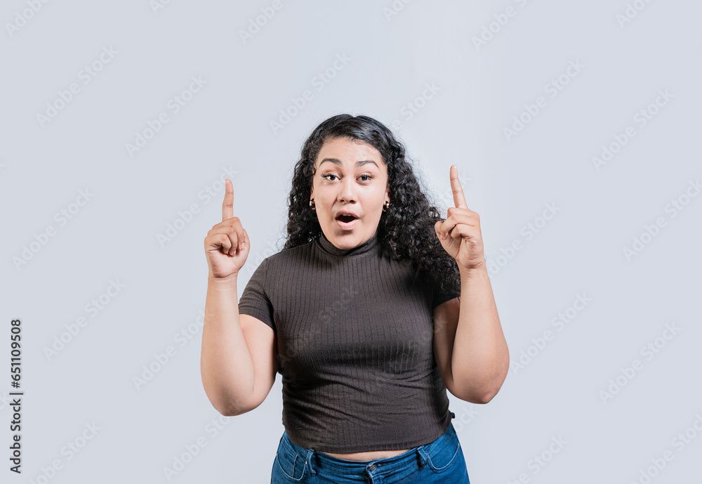 Young latin girl amazed pointing a promotion up isolated. Young curly-haired woman pointing up. Latin people pointing up Young latin girl amazed pointing a promotion up isolated. Young curly-haired woman pointing up. Latin people pointing up