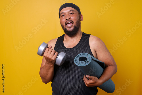 Smiling fat guy in sportswear ready to workout with dumbbells for weight loss.