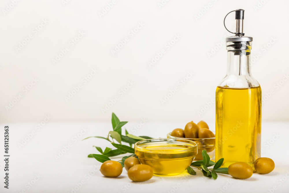 Olive oil in a bottle on a white texture background. Oil bottle with branches and fruits of olives. Place for text. copy space. cooking oil and salad dressing. Olive oil in a bottle on a white texture background. Oil bottle with branches and fruits of olives. Place for text. copy space. cooking oil and salad dressing.