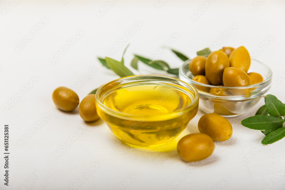 Olive oil in glass bowls, gravy boats and bottle on a textured kitchen table. Oil bottle with branches and fruits of olives. Place for text. copy space. cooking oil and salad dressing.Close-up.Flatley