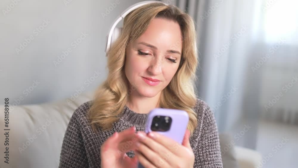 A woman in wireless headphones with a smartphone listens to music. A woman in wireless headphones with a smartphone listens to music.