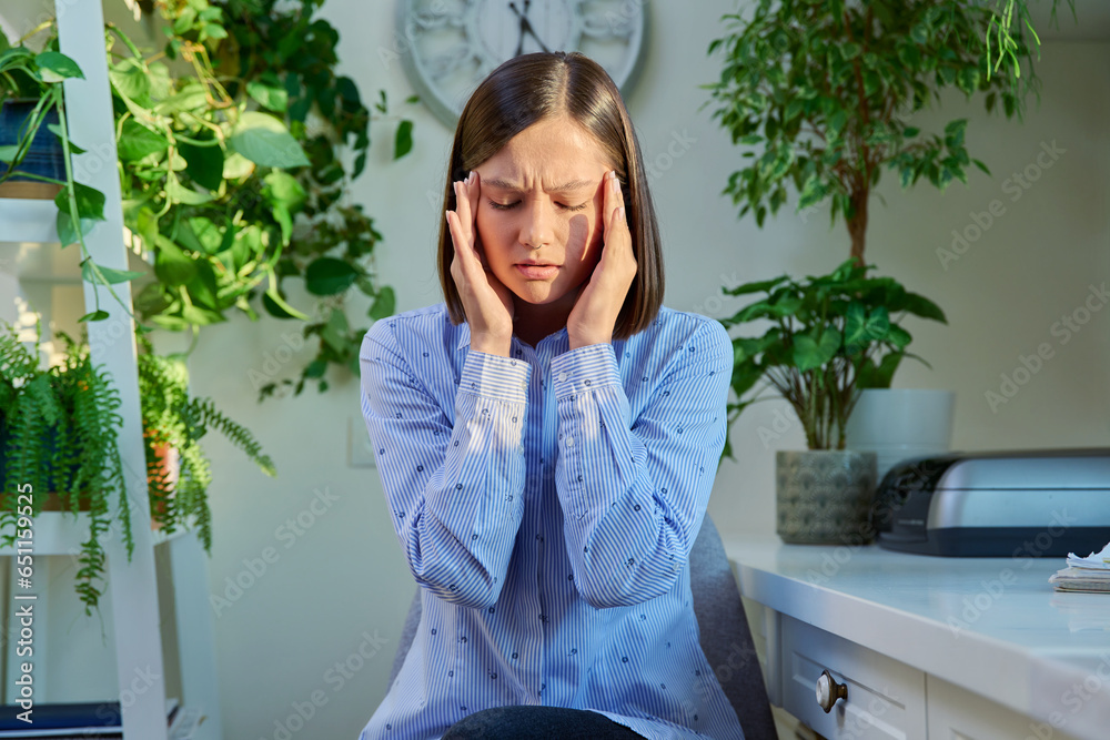 Young woman experiencing stress headache, holding head with hands, at home Young woman experiencing stress headache, holding head with hands, at home